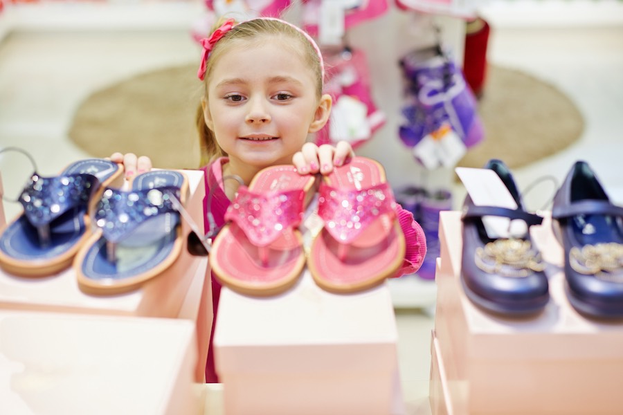 Meisje kijkt naar schoenen in winkel